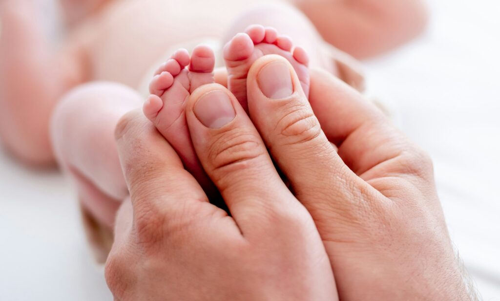 Mother holding newborn baby feet